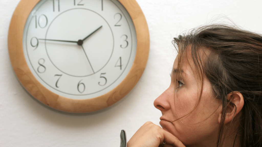 woman looking at clock on the wall waiting