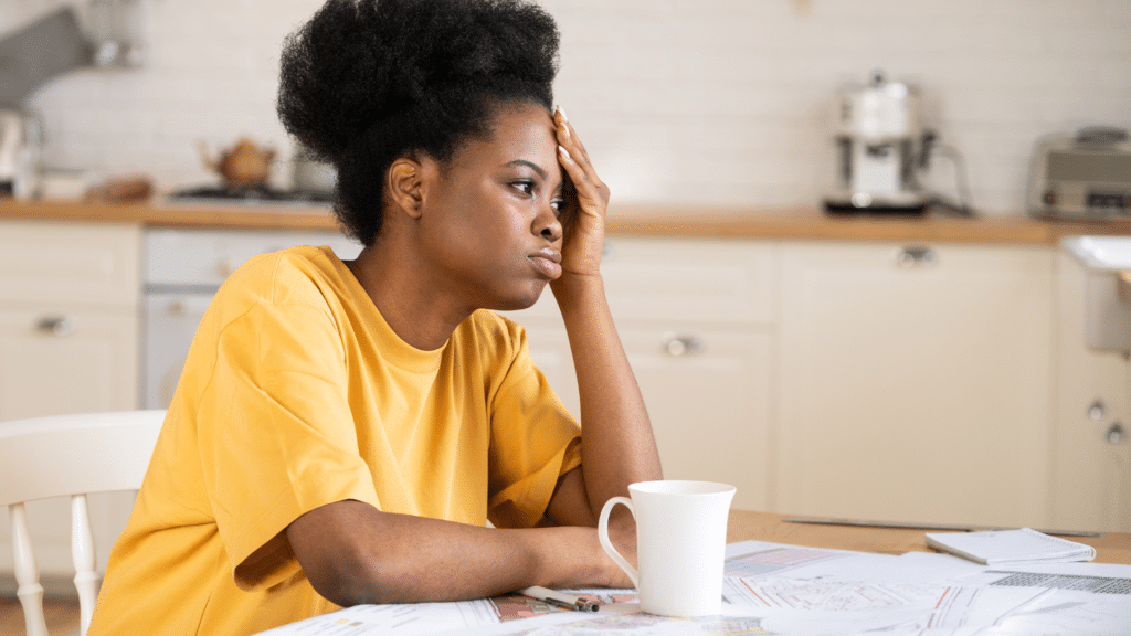 african american woman tired, overwhelmed, drinking coffee in kitchen